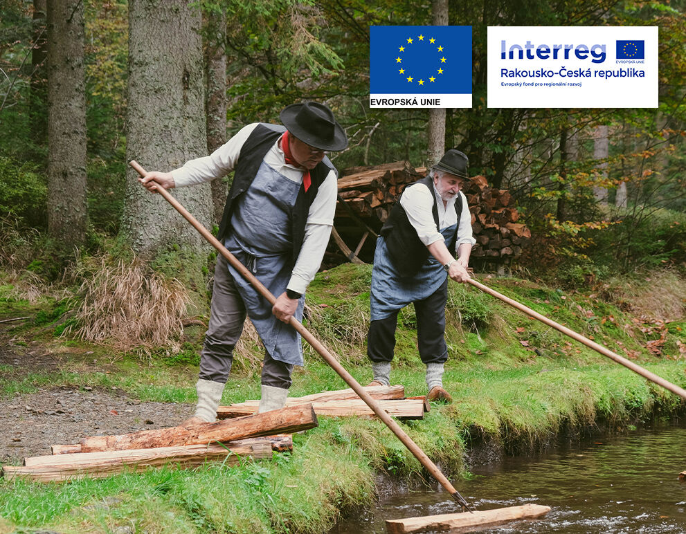 Zwei Arbeiter ziehen in traditioneller Arbeitskleidung Holz aus dem Schwemmkanal